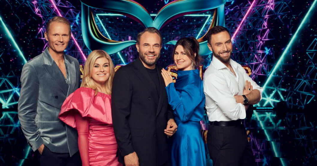 "Masked singer Sveriges" programledare David Hellenius omgiven av panelmedlemmarna Felix Herngren, Pernilla Wahlgren, Nour El Refai och Måns Zelmerlöw. Pressbild. Tv-toppen: "Masked singer" överst