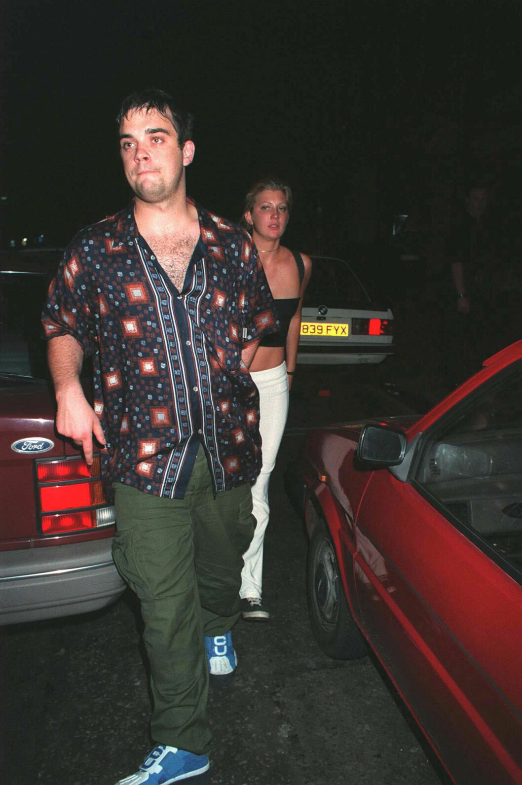 Redan 1999 hade Robbie supit sig plufsig och börjat få rejäla rynkor. ROBBIE WILLIAMS WITH MYSTERY WOMAN