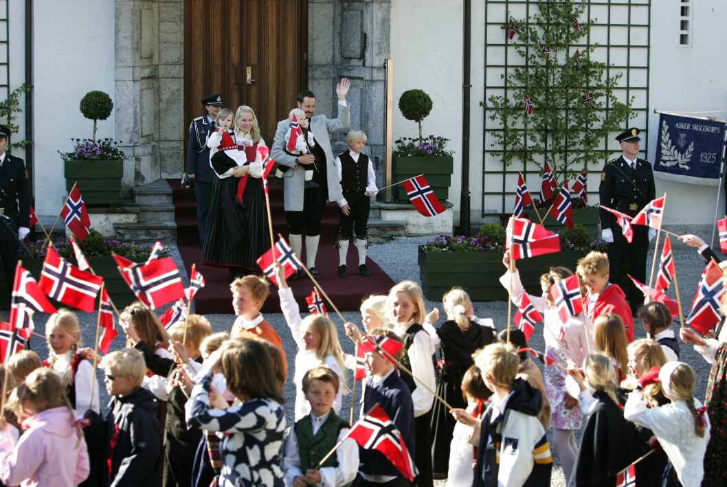 Norska skolelever går i parad under norska nationaldagen. På bild ser vi även Kronprins Haakon, kronprinsessean Mette-Marit, prinsessan Ingrid Alexandra, prins Sverre Magnus och kronprinsessans son Marius Borg vinka till barnen.