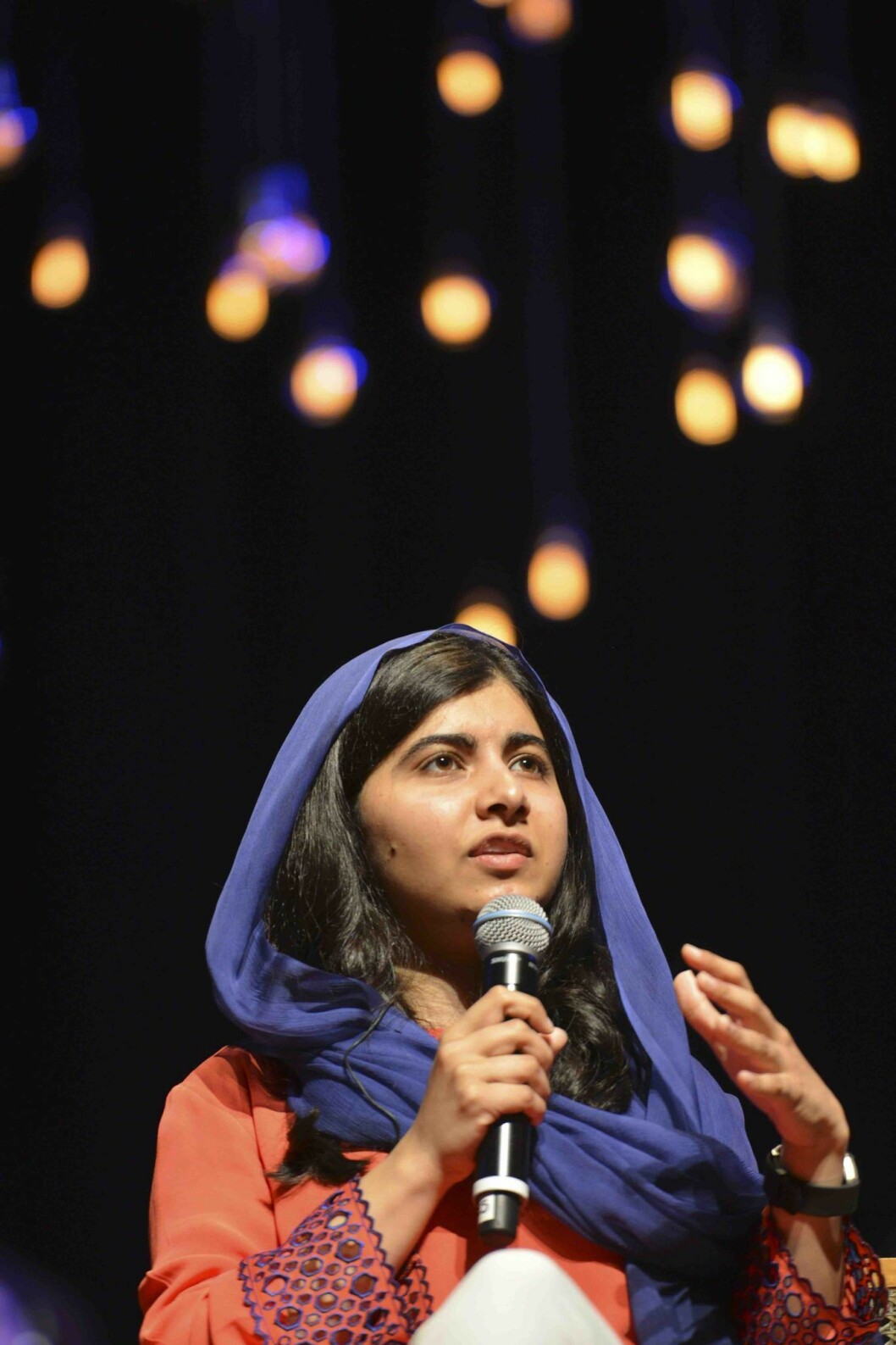 Malala Yousafzai står på scenen och pratar med publiken