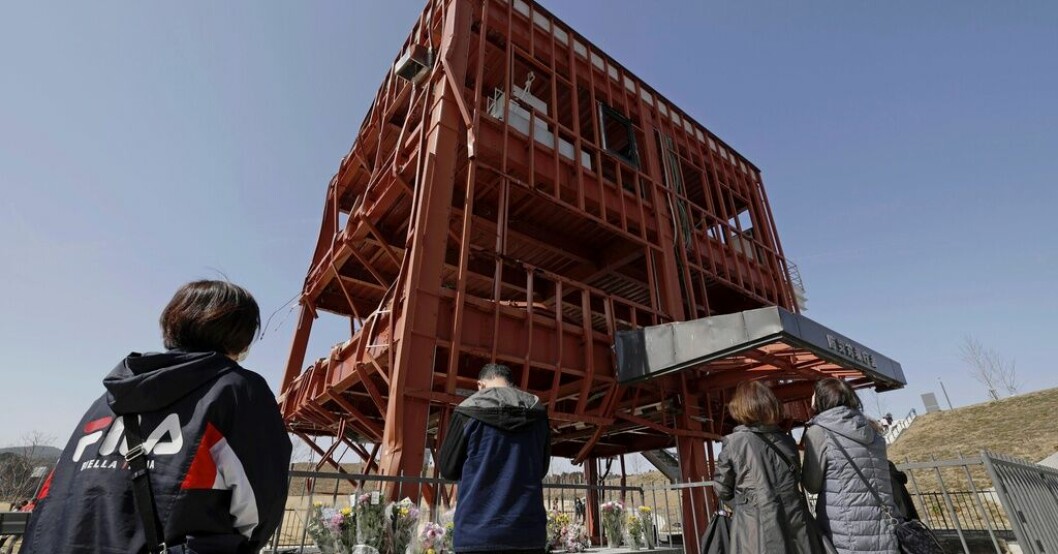 Anhöriga ber på årsdagen i Minamisanriku norr om Fukushima. Den söndertrasade byggnaden tillhörde räddningsverket, och många omkom där i tsunamin 2011. Japaner tror på kärnkraft trots Fukushimakrisen