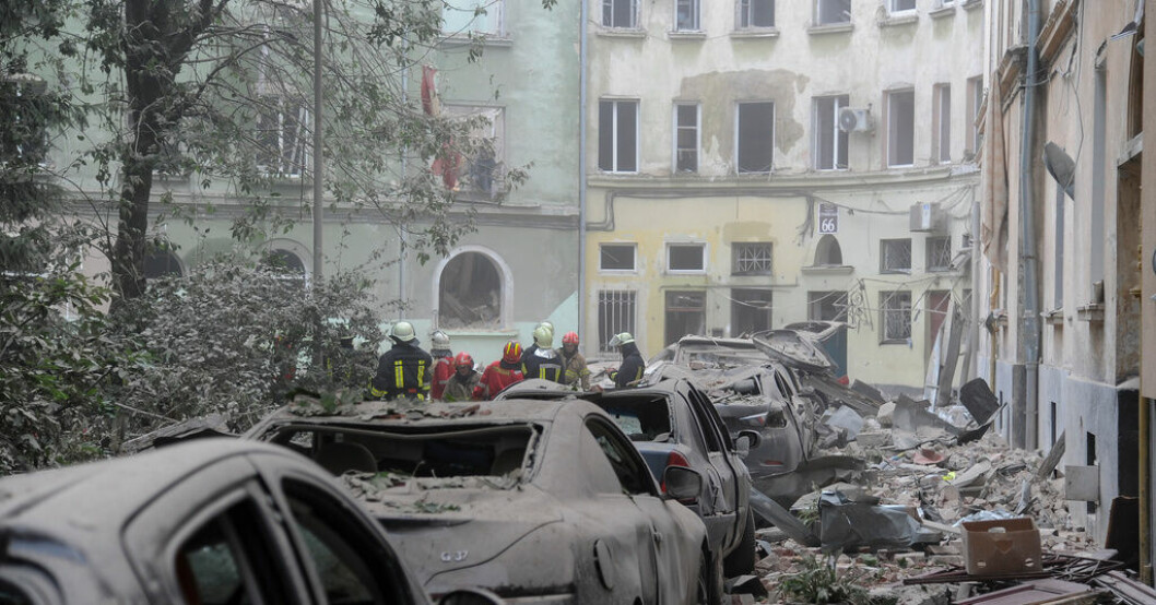 Bråte och havererade parkerade bilar kantar gatan utanför den sönderbombade byggnaden i Lviv. Fem döda efter robotattacken mot Lviv