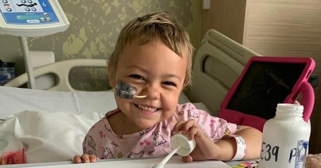 Isla-Mae dog tre gånger under den intensiva cancerbehandlingen och föräldrarna började planera hennes begravning. Isla-Mae sitter i sjukhussängen och ler med slang i näsan.