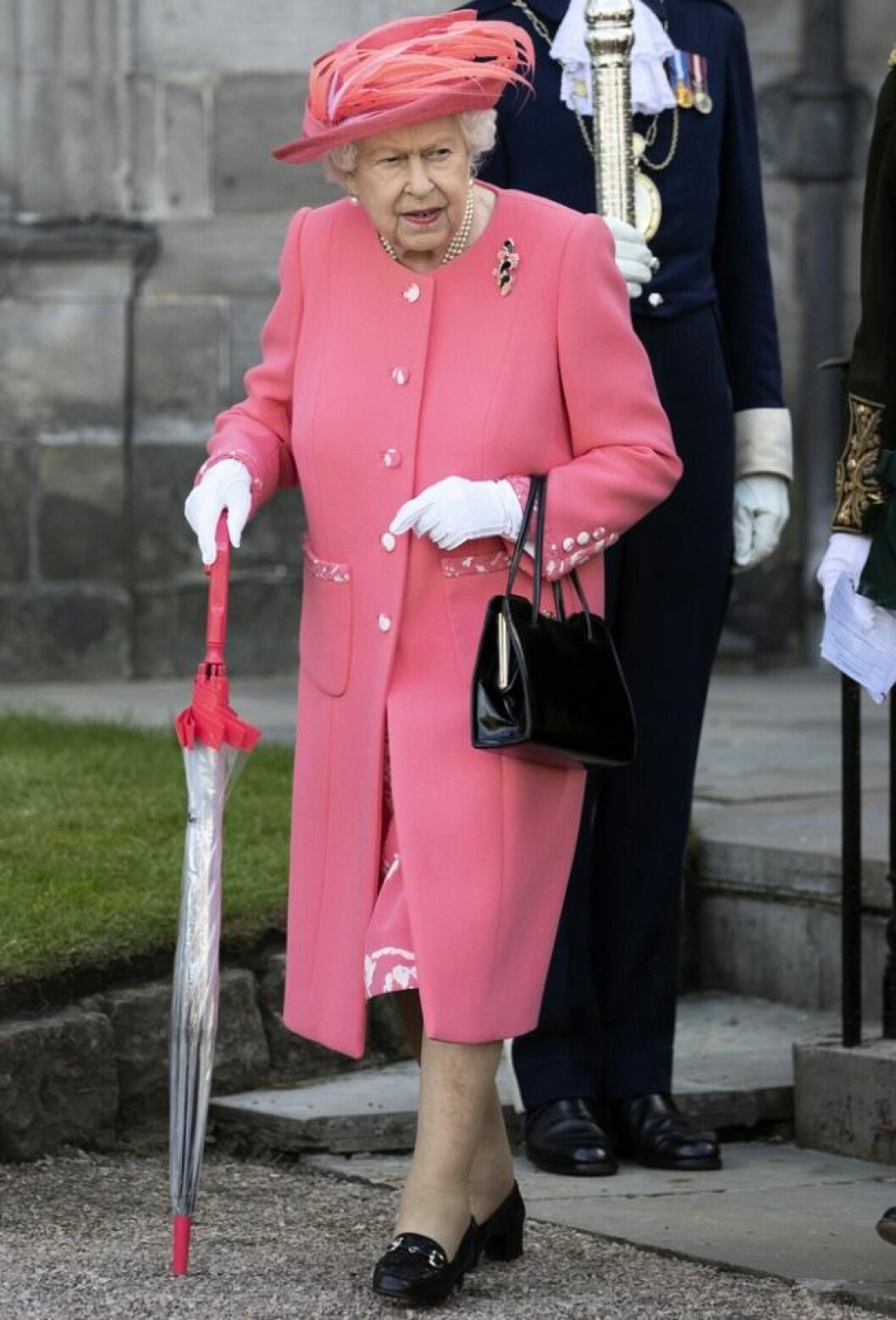 Drottning Elizabeth kommer inte att närvara på dopet. Drottning Elizabeth går med paraply som käpp