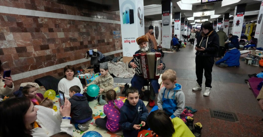 En äldre man spelar dragspel för barnfamiljer som sökt skydd i en gångtunnel under Charkiv. Arkivbild. 900 timmar i bombskydd för ukrainska barn