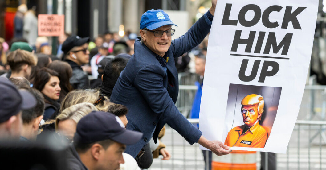 En demonstrant håller en skylt utanför Trump Tower i New York på måndagen. 36 000 poliser beredda – i dag åtalas Trump