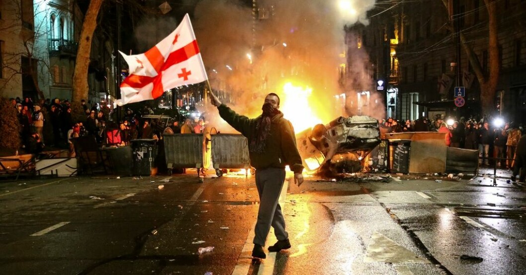 En demonstrant med en georgisk flagga i Tbilisi natten till torsdagen, före de nya beskeden om lagen. Ny protest utlovas – trots reträtt om agentlag