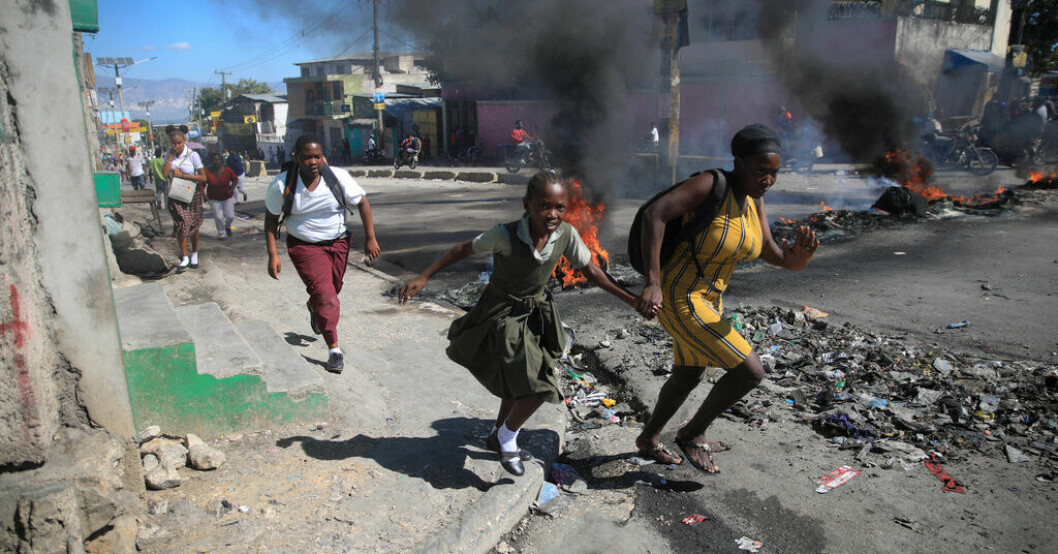 En kvinna och hennes dotter springer förbi en avspärrning på en gata i Haitis huvudstad Port-au-Prince den 26 januari. Våldtogs i tre dagar – kvinnor måltavlor i Haiti