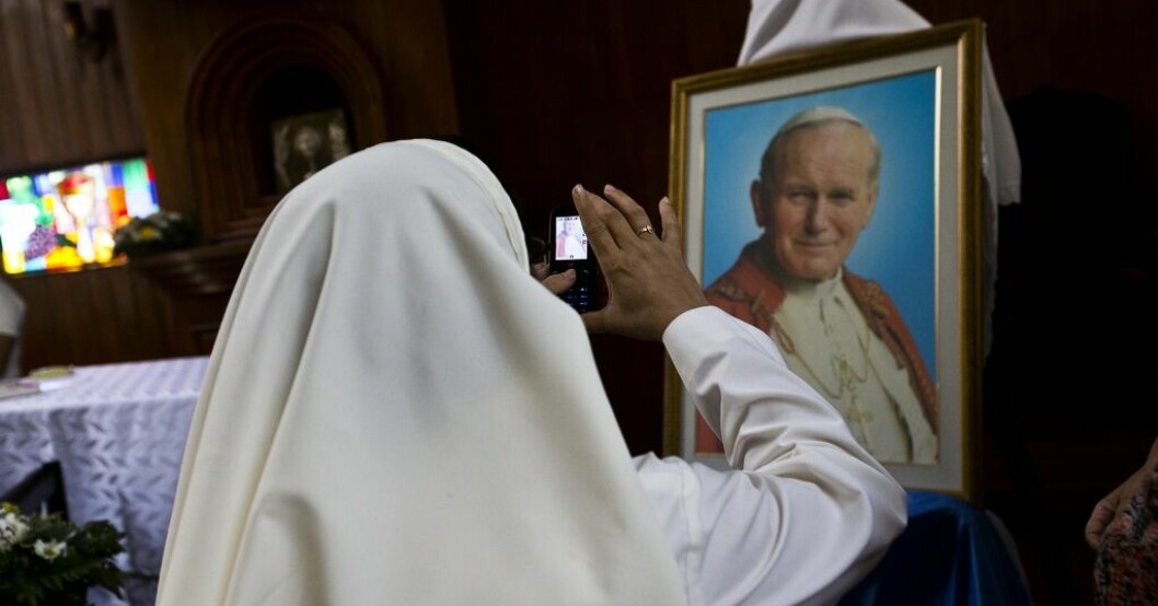 En nunna i Nicaraguas huvudstad Managua tar en bild på ett porträtt av den tidigare påven Johannes Paulus i en katedral 2015. Påven i storbråk – jämförde ledare med Hitler
