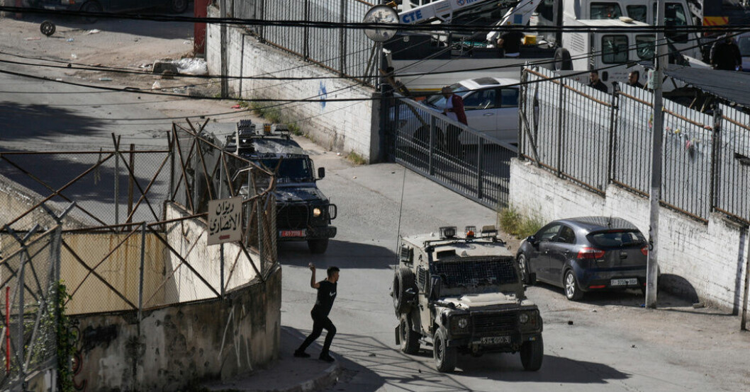 En palestinsk man kastar sten mot en konvoj med israeliska militärfordon under torsdagens räd mot Nablus. Israel: Mordmisstänkta palestinier ihjälskjutna