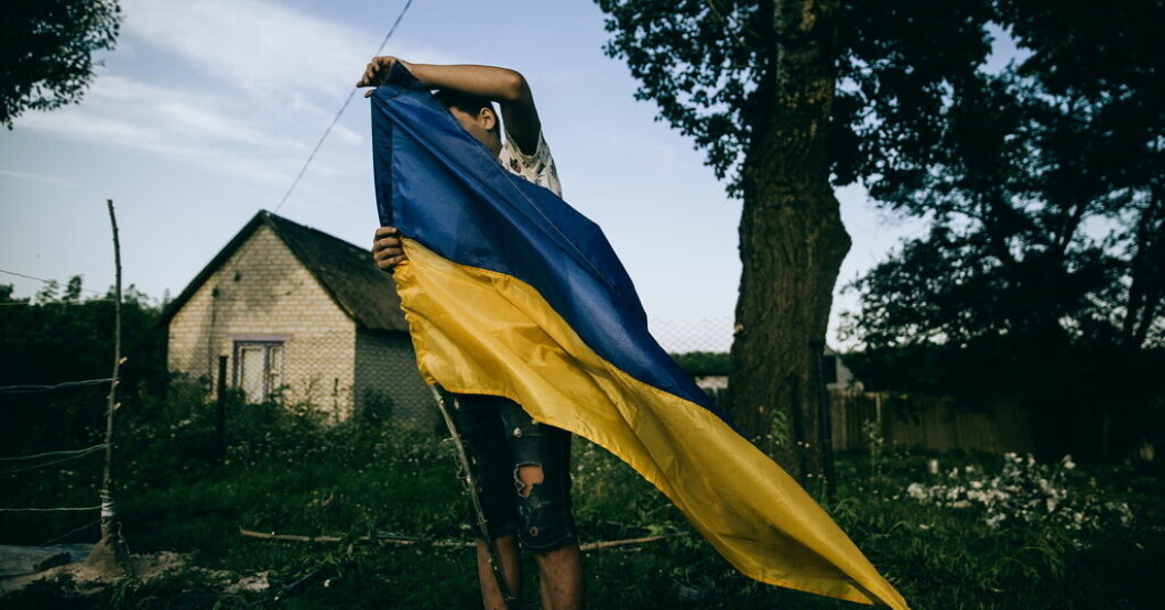 Ett barn sätter upp en ukrainsk flagga som "checkpoint" i byn Zelene i Charkiv-regionen. Ukrainska fotografer visar kriget inifrån