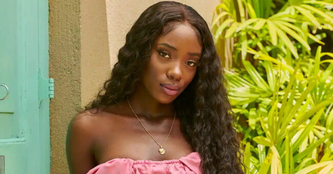 Awa Touray, 24, är modell och konsult. Awa Touray klädd i en rosa klänning framför en blå dörr och grönska.