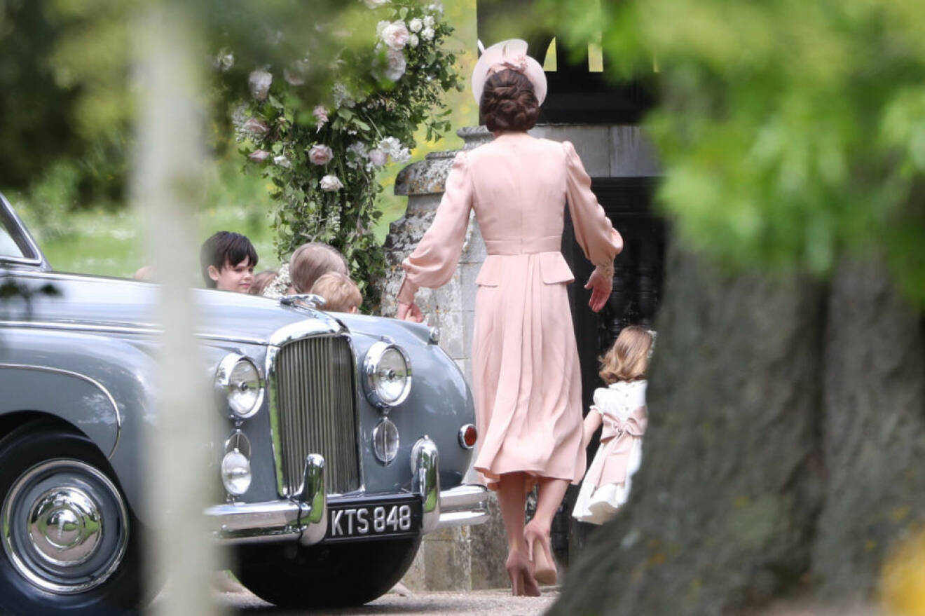 Hertiginnan Kate Middleton går in i kyrkan med sina barn prins George och prinsessan Charlotte, som båda ska vara brudnäbbar. 