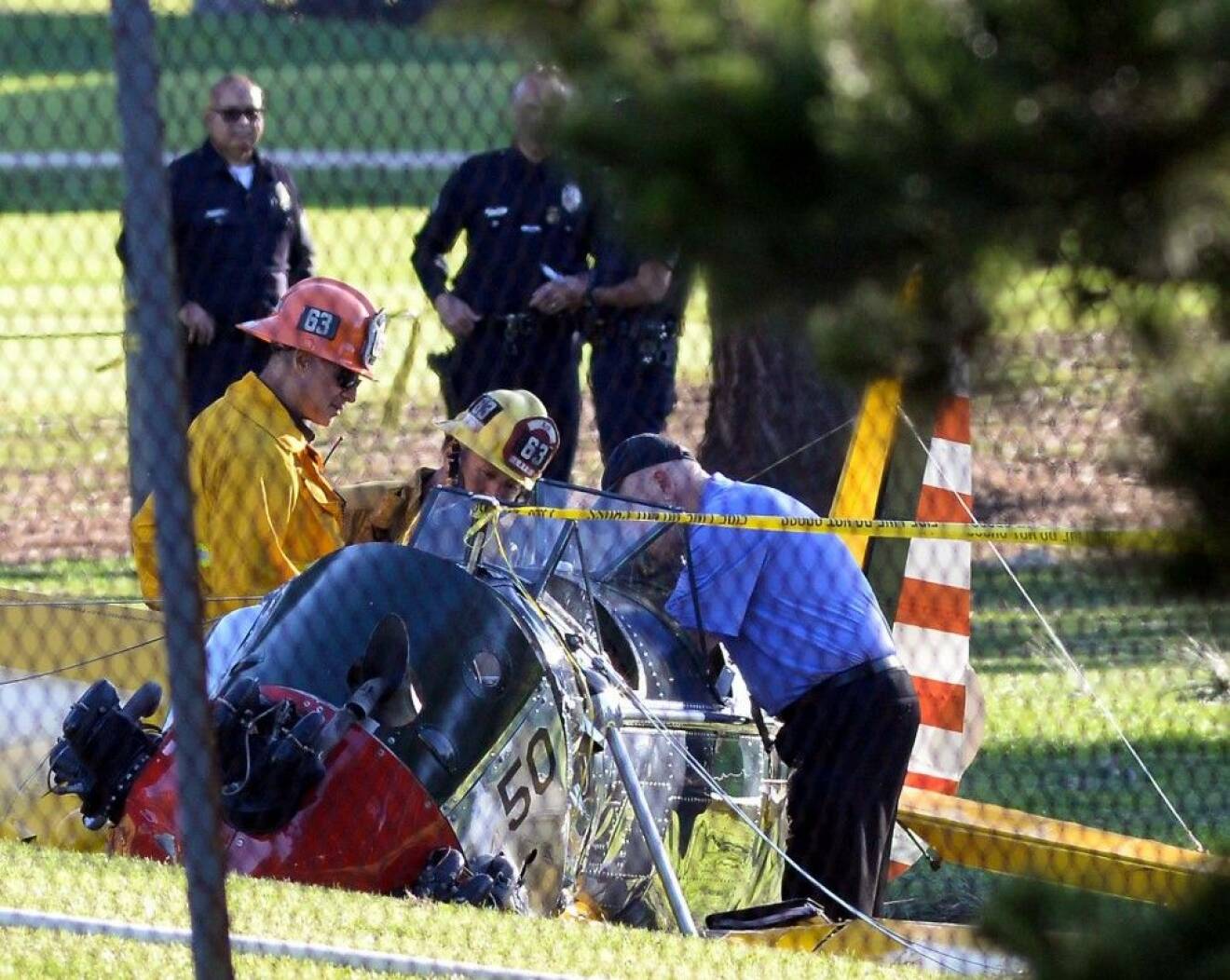 Firefighter and investigaters look over the wreckage of Harrison Ford's vintage airplane which crashed on the Penmar Golf course in venice, Ca