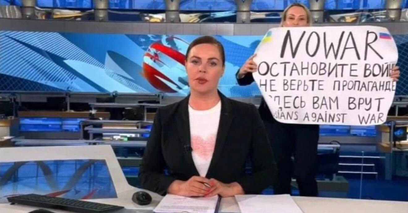 Tv-redaktören håller upp en skylt bakom programledaren som en protest mot Putins krig mot Ukraina.
