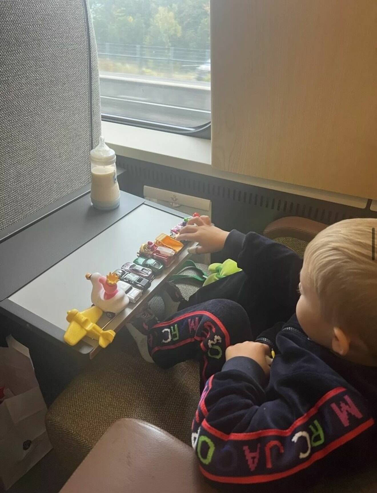 Alvin på tåget med sin mamma när han ställt upp flera leksaker på bordet.