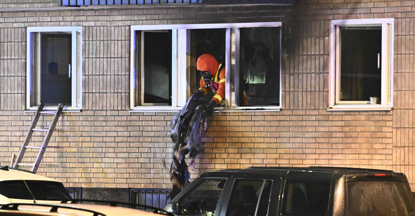 En brandman slänger ut massa som har brunnit genom ett fönster.