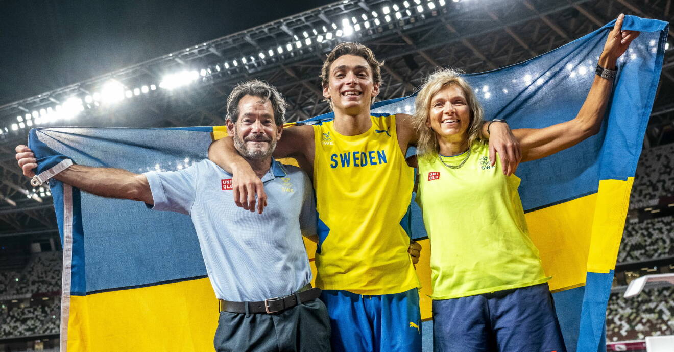 Greg, Armand och Helena Duplantis håller upp en flagga bakom sig.