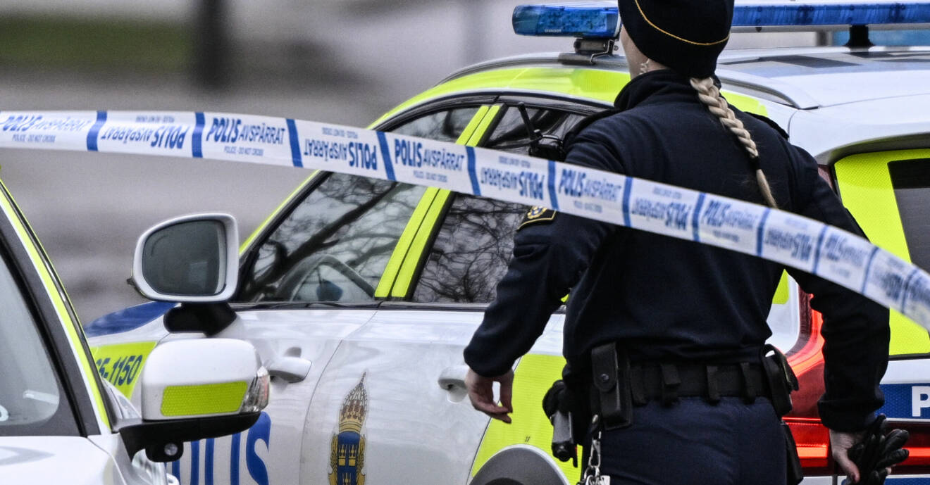 En polis framför en polisbil och polisavspärrningsband.
