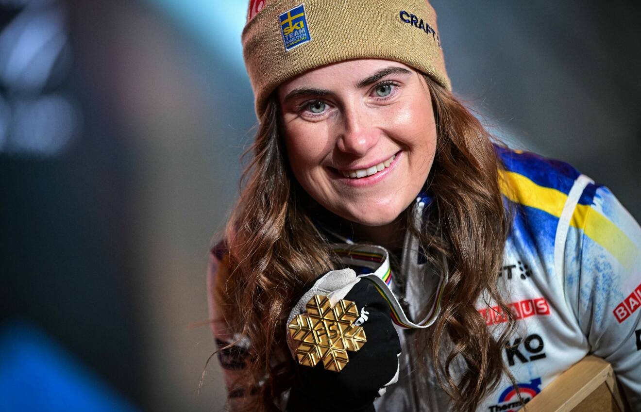 Ebba Andersson poserar med guldmössa och medalj efter vinsten i damernas tremil.