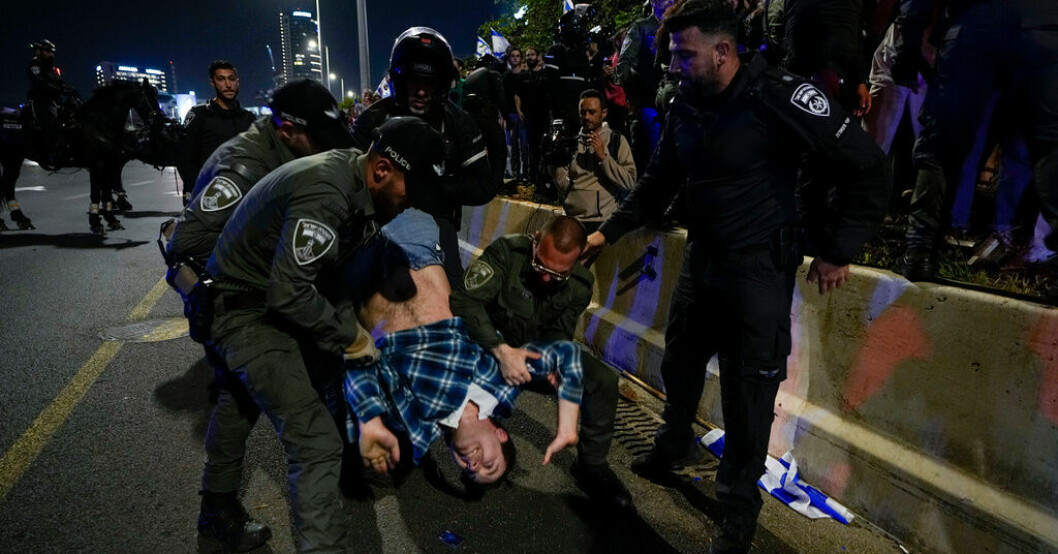 Israelisk polis flyttar på demonstranter som blockerar en motorväg invid Tel Aviv under en protest mot den israeliska regerings planer på att förändra rättsväsendet. Tiotusentals demonstrerar i Tel Aviv