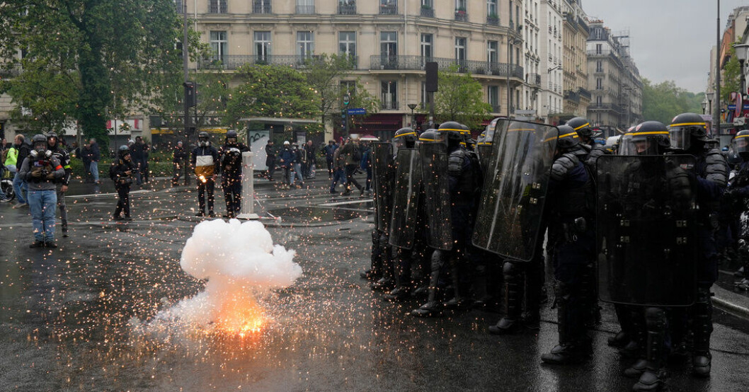 Kravallpoliser skyddar sig från ett sprängämne som kastats mot dem i Paris. Över 100 poliser sårade i franska protesterna