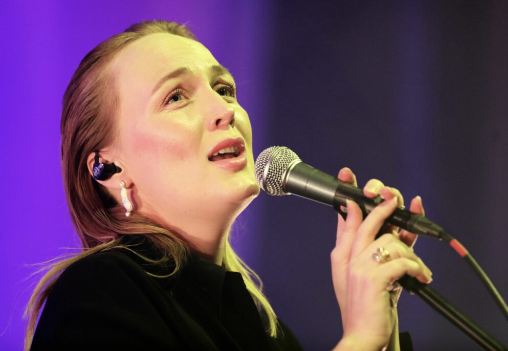 Moonica Mac. Monica Mac sjunger med lila bakgrund
