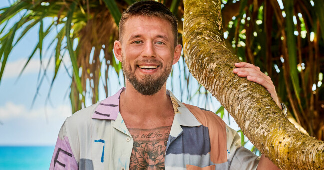 Niklas Hammarberg, 31. Niklas i en öppen skjorta framför en strand.