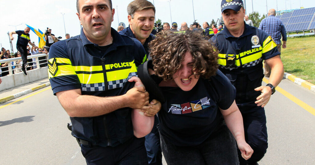 Polis för bort en demonstrant i Tbilisi. Protester mötte ryska plan i Georgien