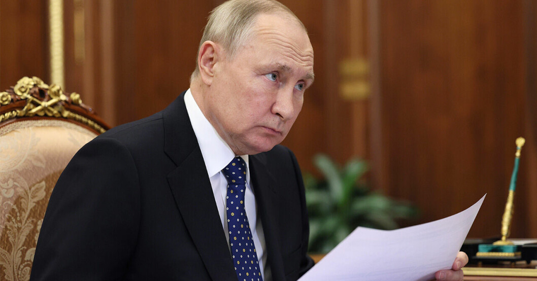 Vladimir Putin ser ledsen ut på möte med papper i handen.