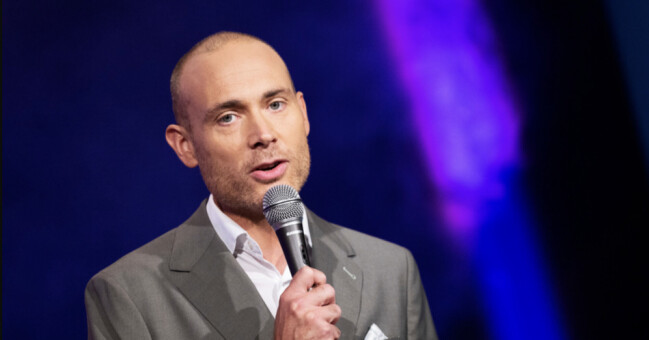Jesper Rönndal är en av programledarna för Melodifestivalen år 2023! Jesper Rönndahl håller i en mick.