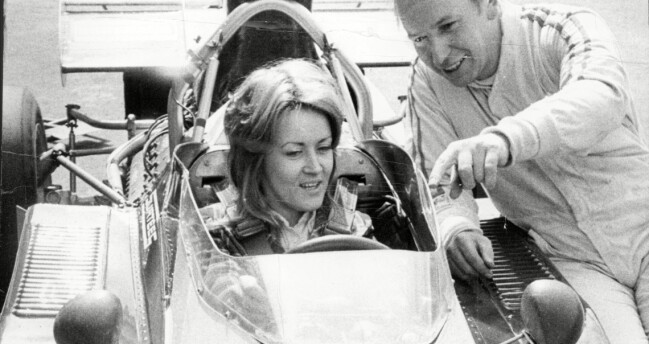 Sue Baker får en visning av hur en Formel 1-bil fungerar av racerföraren John Surtees. Bilden är tagen 1972.