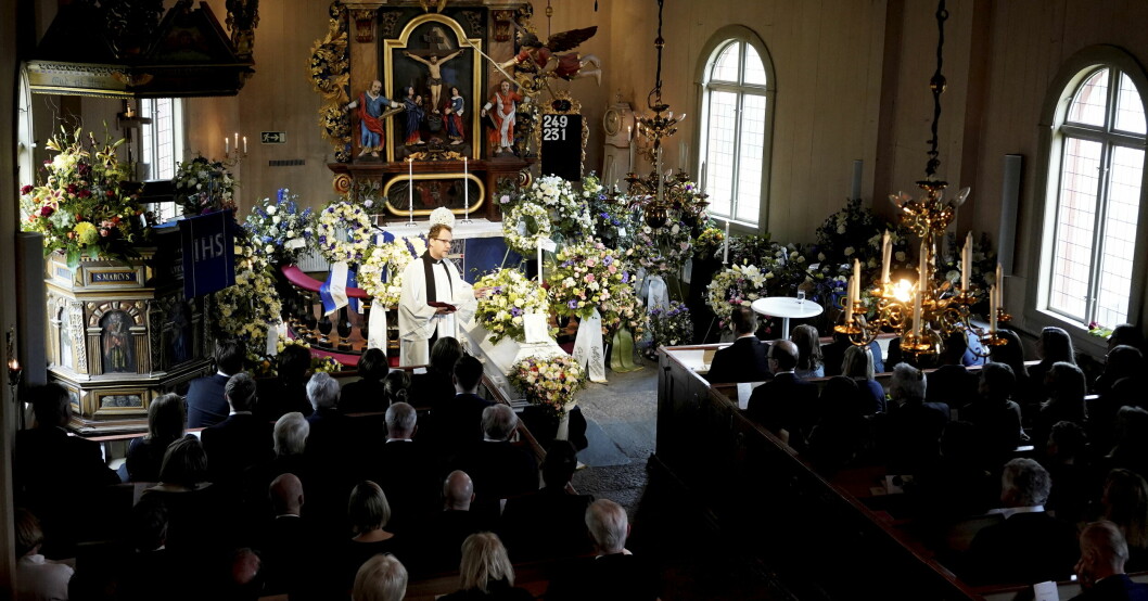 Fullt i kyrkan, vid kistan syns prästen.