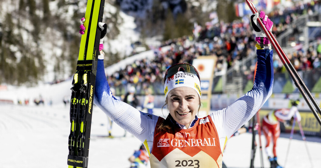 Ebba Andersson efter sin historiska vinst. Ebba Andersson håller upp sina stavar och skidor efter vinsten.
