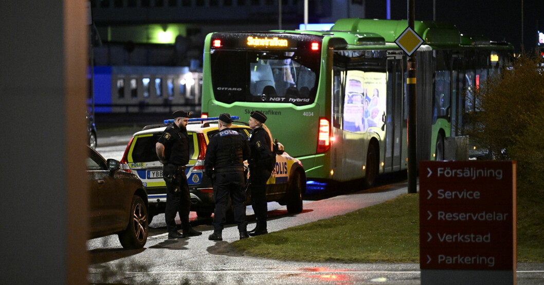 Poliser vid en polisbil bakom en buss.