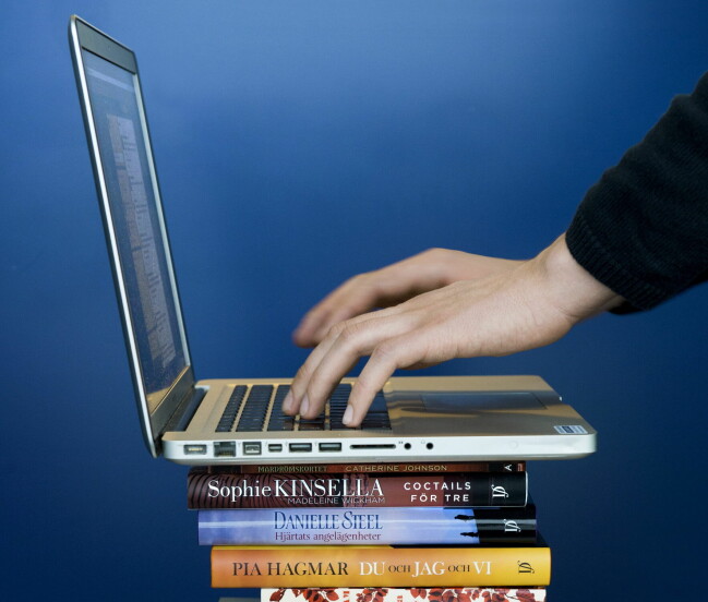 ChatGPT kan hjälpa dig att skriva en hel bok. En som skriver på en laptop på en bokhög.
