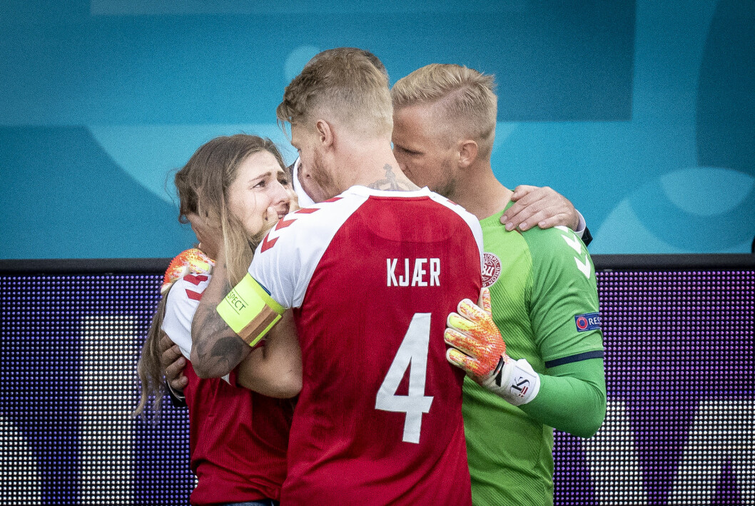 Simon Kjær och Kasper Schmeichel tröstar Christian Eriksens fru Sabrina Kvist Jensen. Simon Kjær och Kasper Schmeichel tröstar Christian Eriksens fru Sabrina Kvist Jensen.