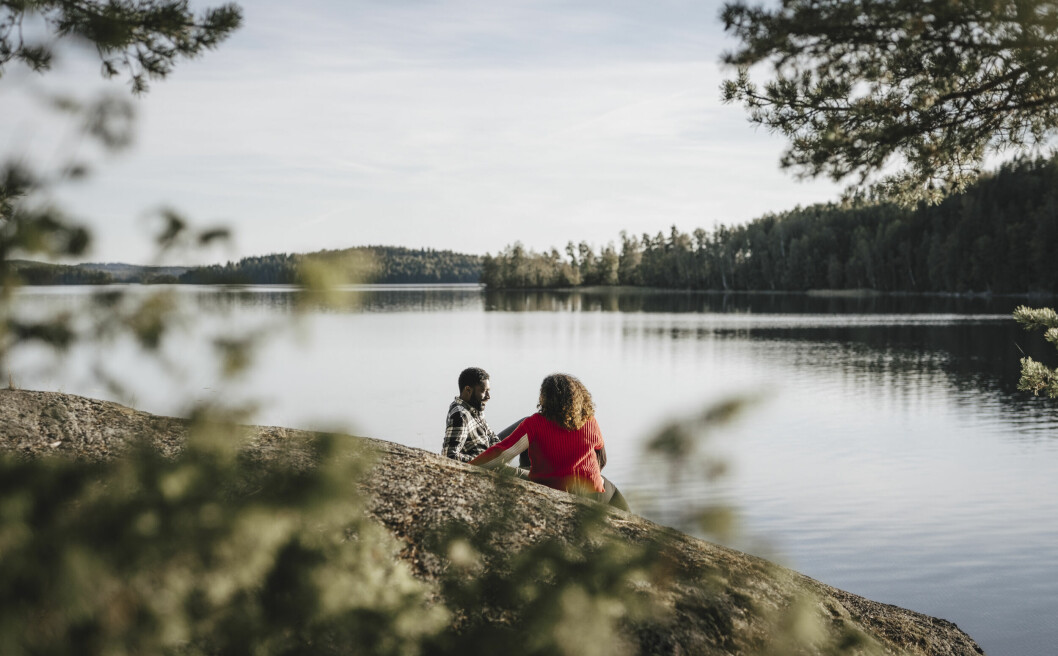 <strong>Lägger du dina semesterdagar smart kan det blir långledigt runt exempelvis nationaldagen.</strong> Par sitter på en stenhäll vid vattnet.