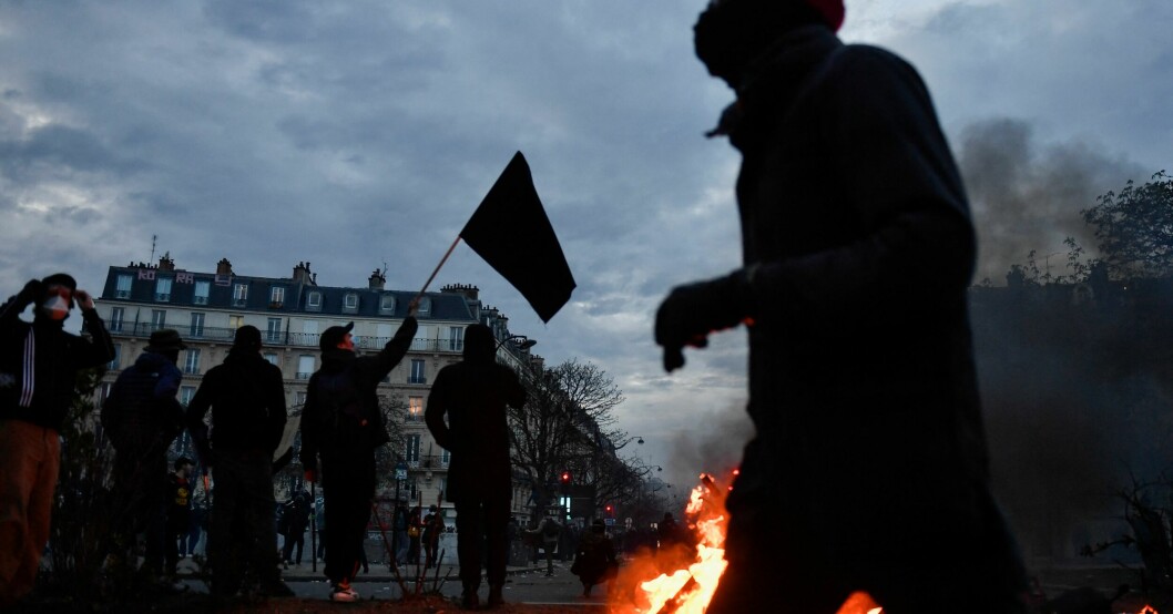 A protestor walks past burning scooters during a demonstration after the government pushed a pensions reform through parliament without a vote, using the article 49.3 of the constitution, in Paris on March 28, 2023. - France faces another day of strikes and protests nearly two weeks after the president bypassed parliament to pass a pensions overhaul that is sparking turmoil in the country, with unions vowing no let-up in mass protests to get the government to back down. The day of action is the tenth such mobilisation since protests started in mid-January against the law, which includes raising the retirement age from 62 to 64. (Photo by JULIEN DE ROSA / AFP)