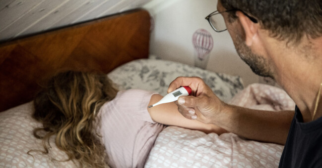 Det råder stor brist på flytande febernedsättande paracetamol på Sveriges apotek. En man håller i en termometer och en liten flicka ligger i en säng.