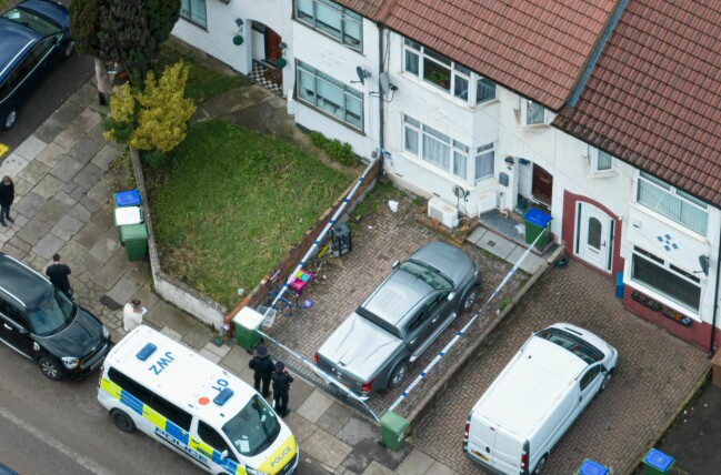 Polisen har spärrat av radhuset där den svenskan mamman och hennes två söner hittades döda. Avspärrningsband, poliser och en polisbil utanför radhuset där det hände.
