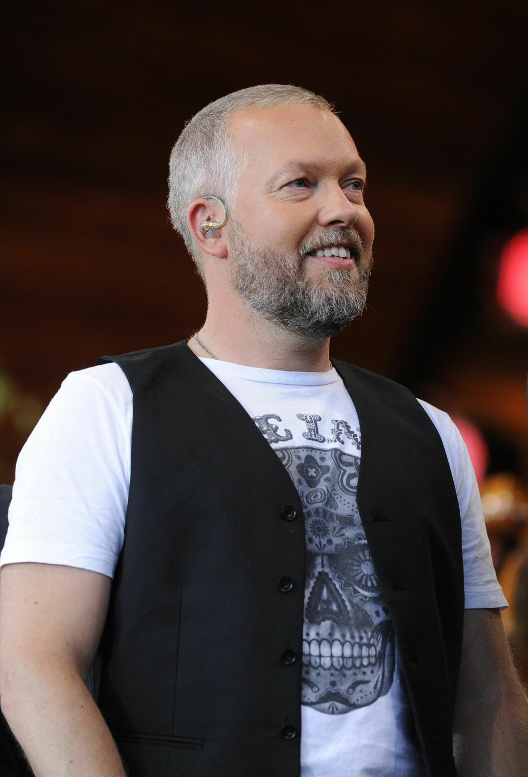 Tommy Carlsson. Tommy Carlsson i Arvingarna skrattar från scen, han har skägg och rakat hår