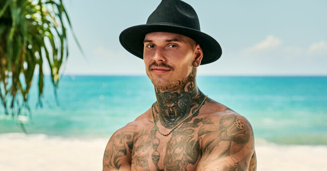 Simon Olsson Bull, 32. Simon med massa tatueringar framför en strand.