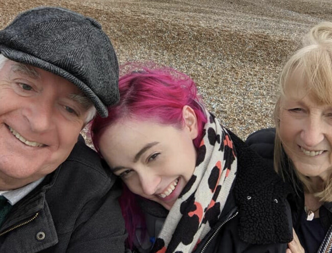 Emma på en strand med sina föräldrar.