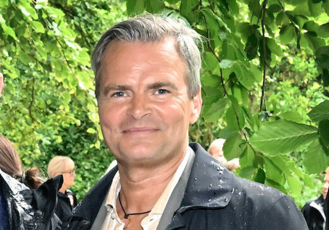 Gekås ägare Thomas Karlsson. Thomas Karlsson tittar in i kameran och ler med gröna löv i bakgrunden.