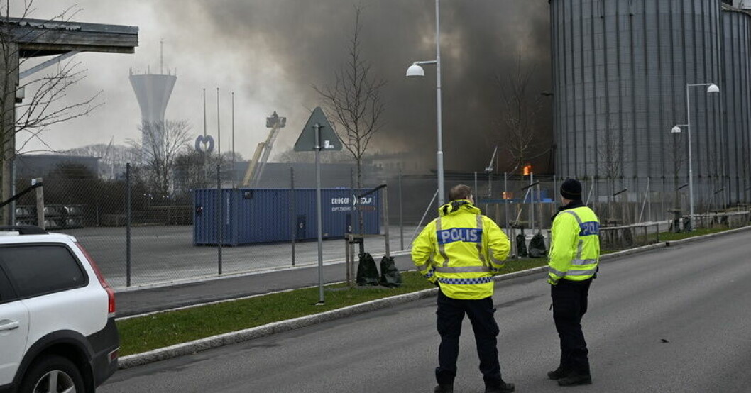 Två poliser står och tittar på svart rök från branden.