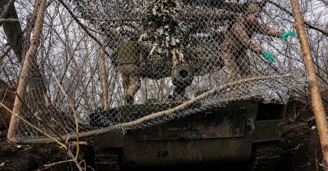 Ukrainska soldater täcker en artilleripjäs för att den ska bli svårare att upptäcka för Rysslands så kallade kamikazedrönare. Bilden togs vid fronten i Bachmut i fredags. Blodiga strider när Bachmut håller ut
